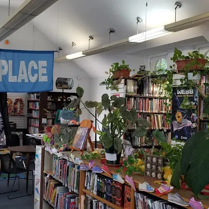 Library interior with bookshelves, leafy plants and a blue banner inside the Darby Free Library
