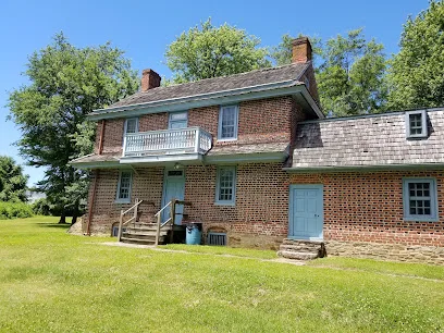 Two-story brick colonial house with a white balcony and slate-roofed wing, Morton Morton House, seen across a lawn