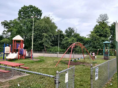 Playground with slides, a red swing set and a picnic table at Scullion Recreation Area, surrounded by trees